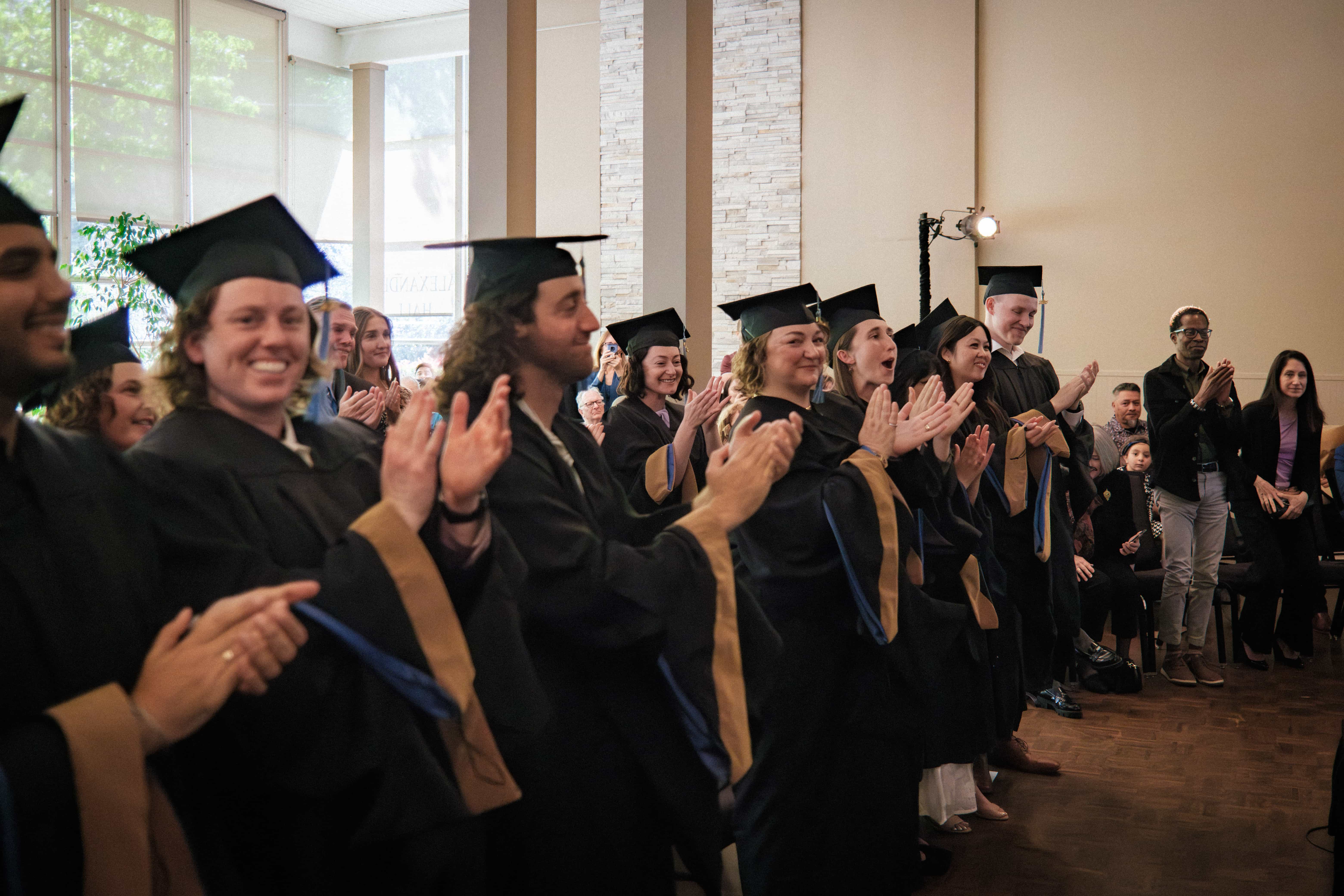 a group of people in graduation gowns and caps clapping