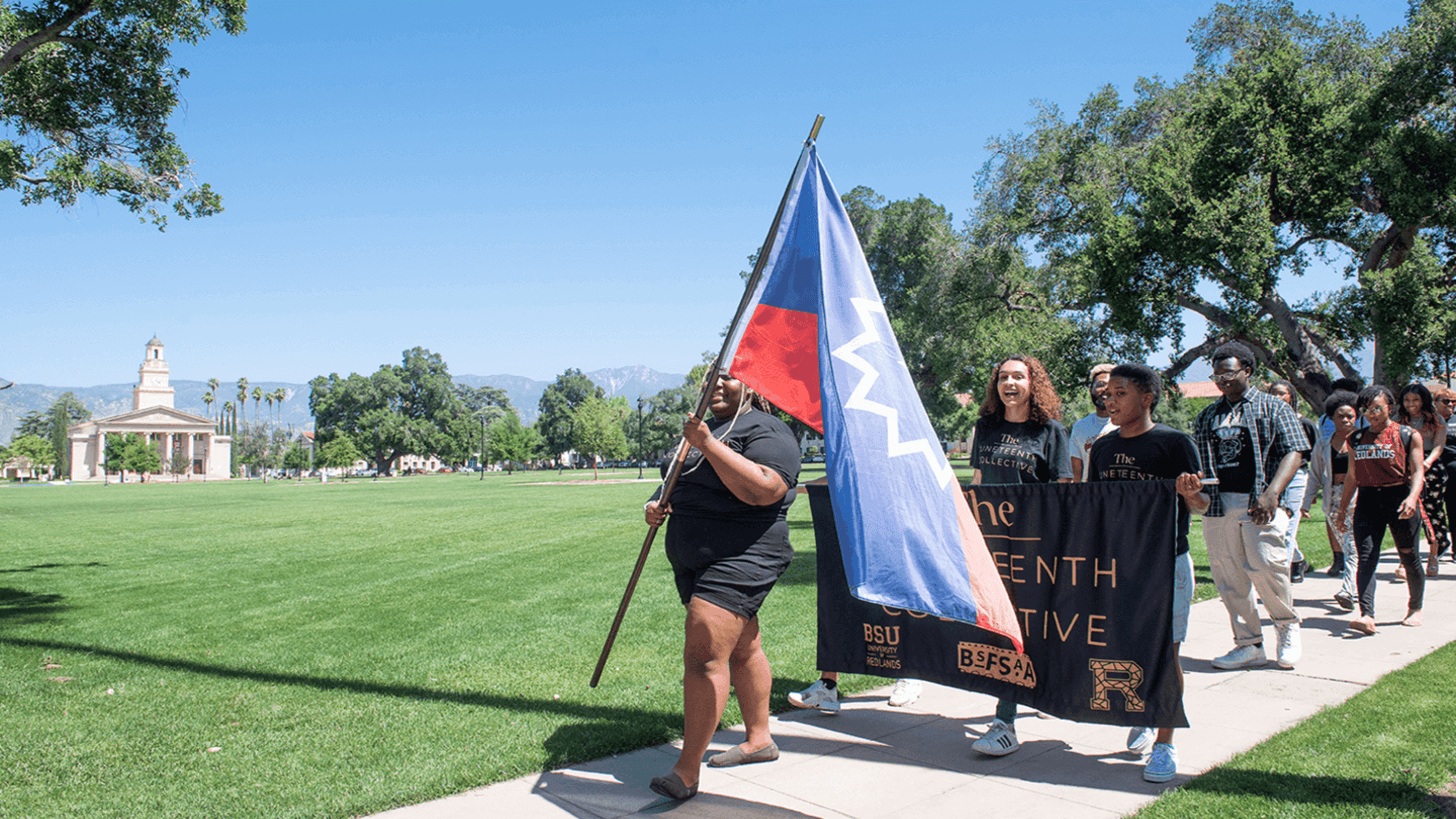 a group of people standing on a sidewalk holding a flag