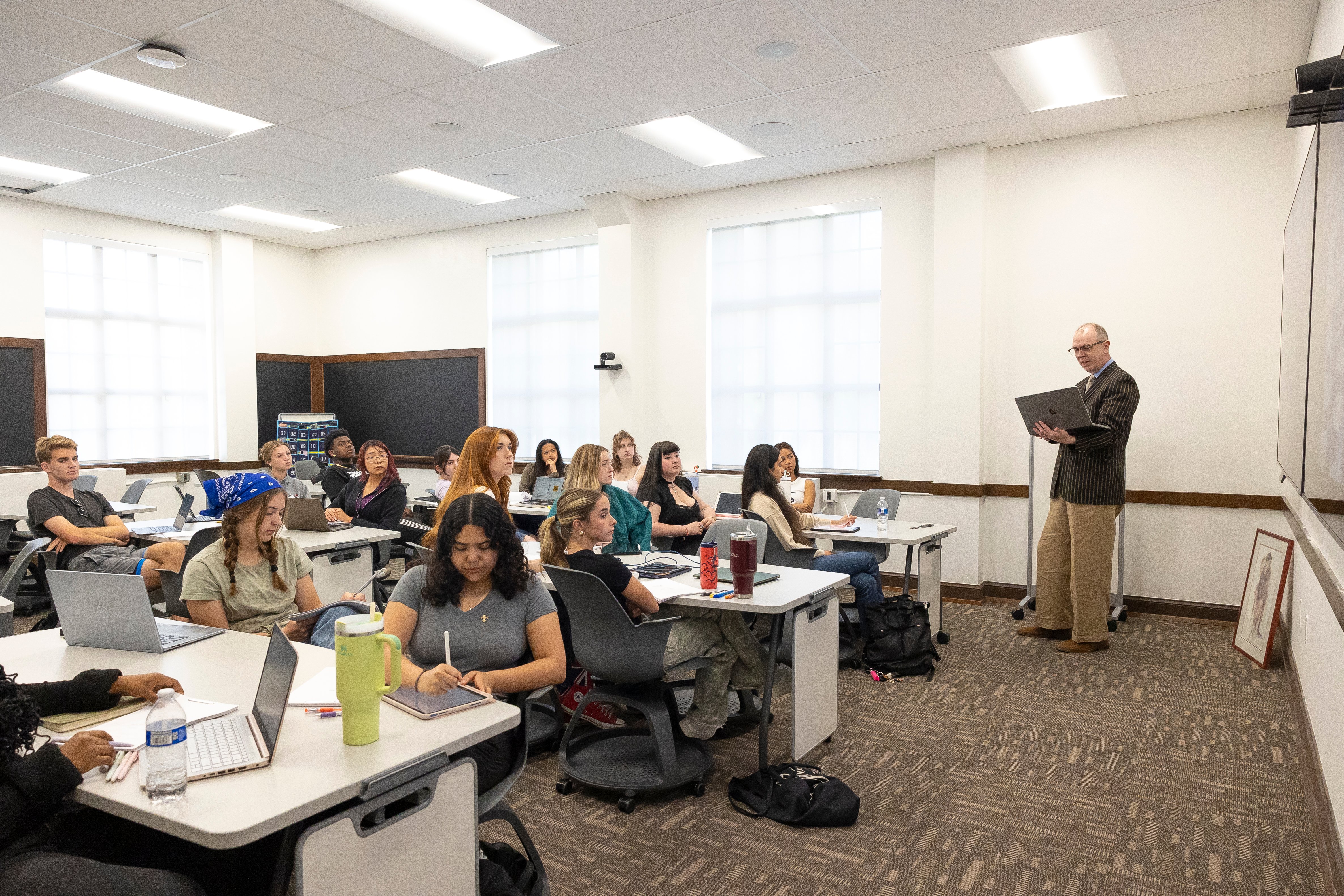 a person standing in front of a group of people in a classroom
