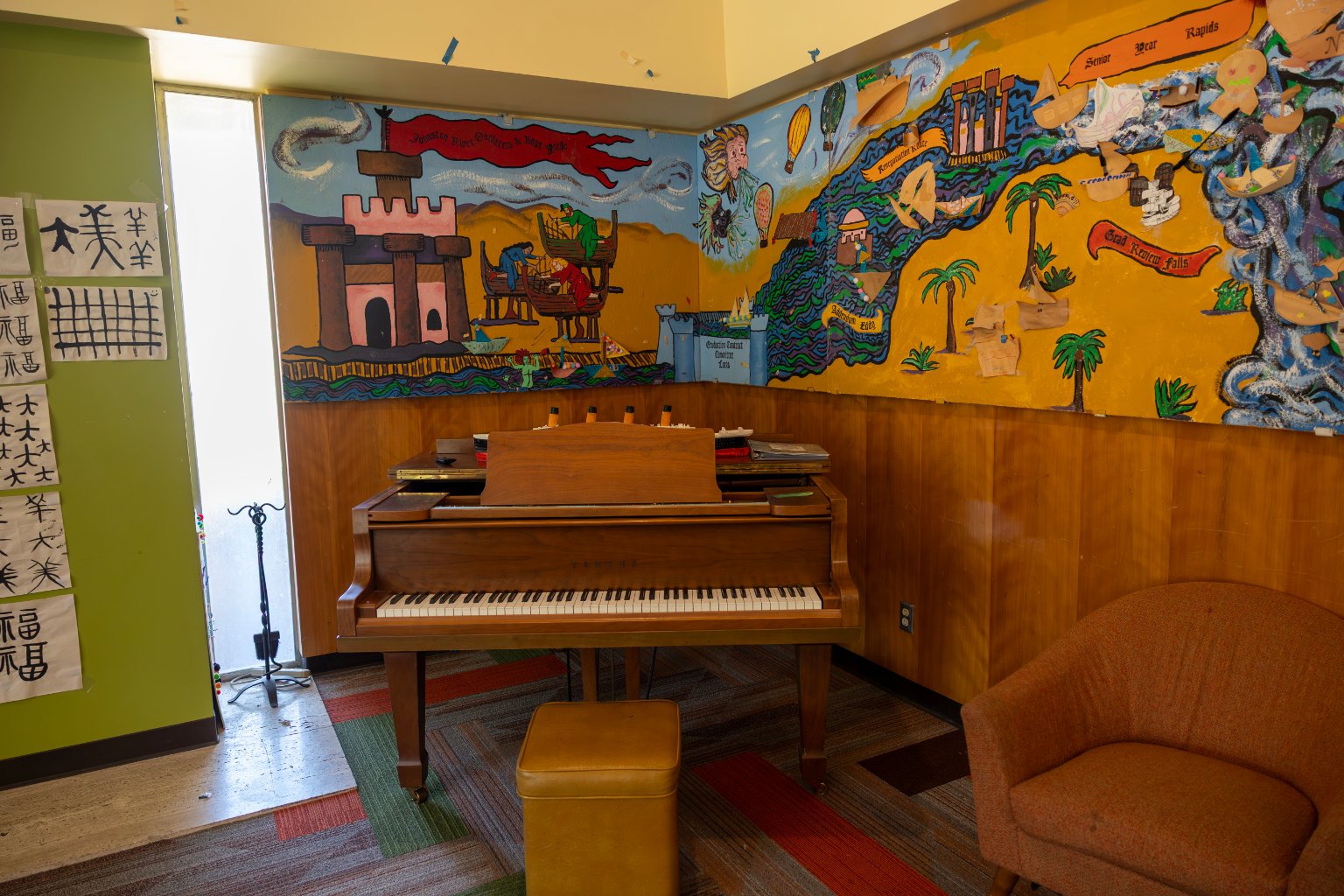 a piano in a room with a mural on the wall