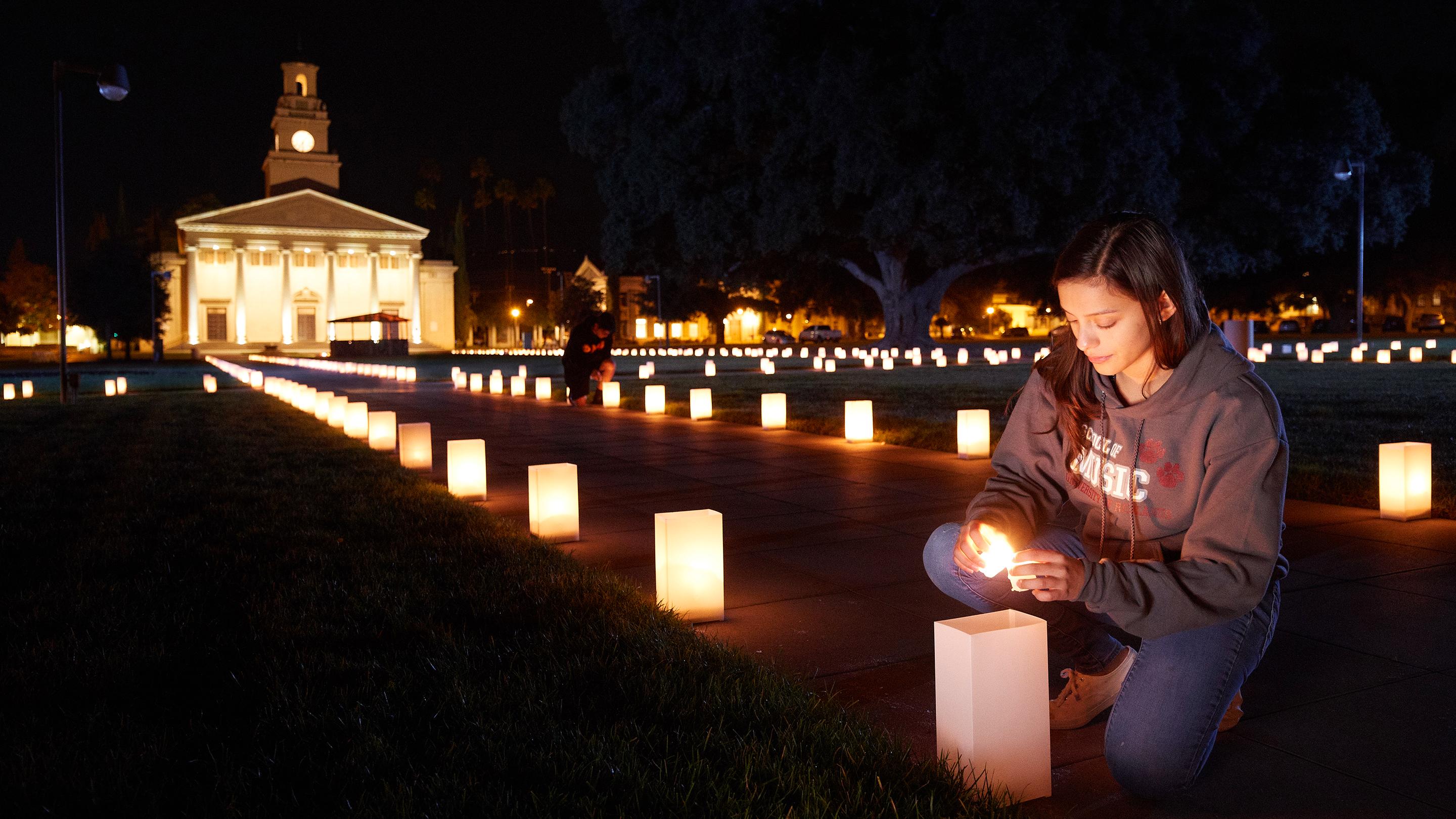 a person sitting on a sidewalk with a candle in the middle