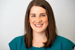 a woman with brown hair wearing a teal shirt