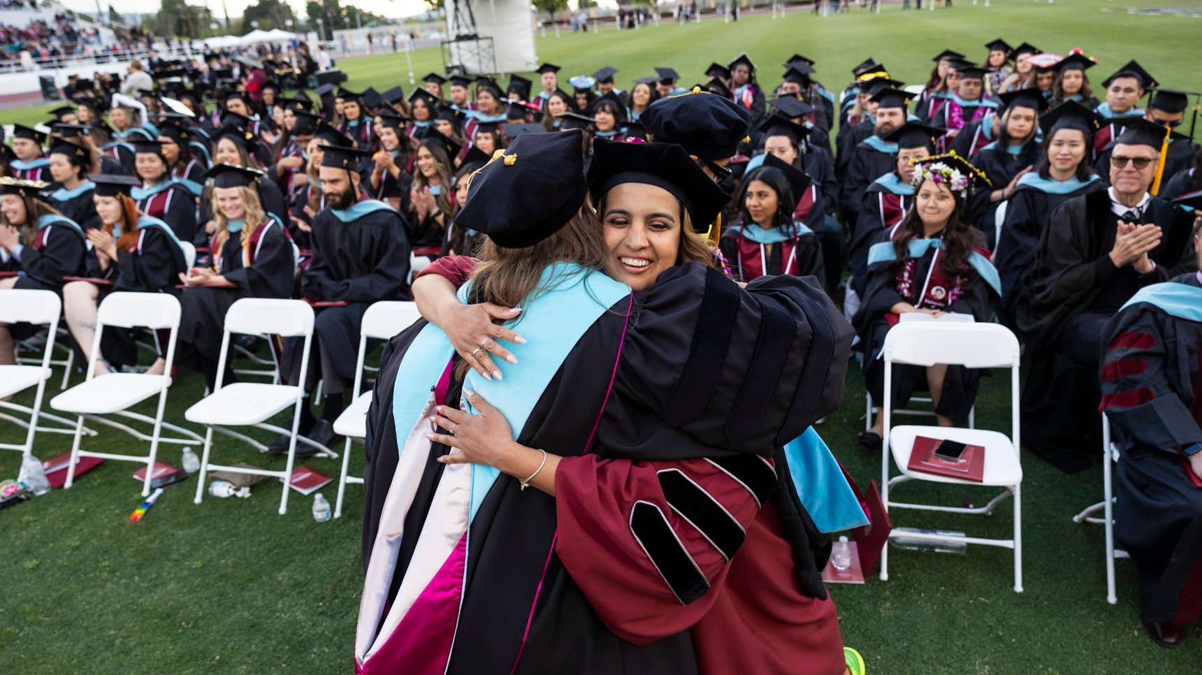 a woman hugging another woman in graduation gowns