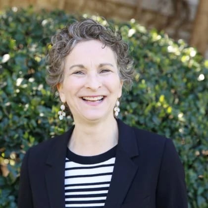 a person smiling in front of a bush