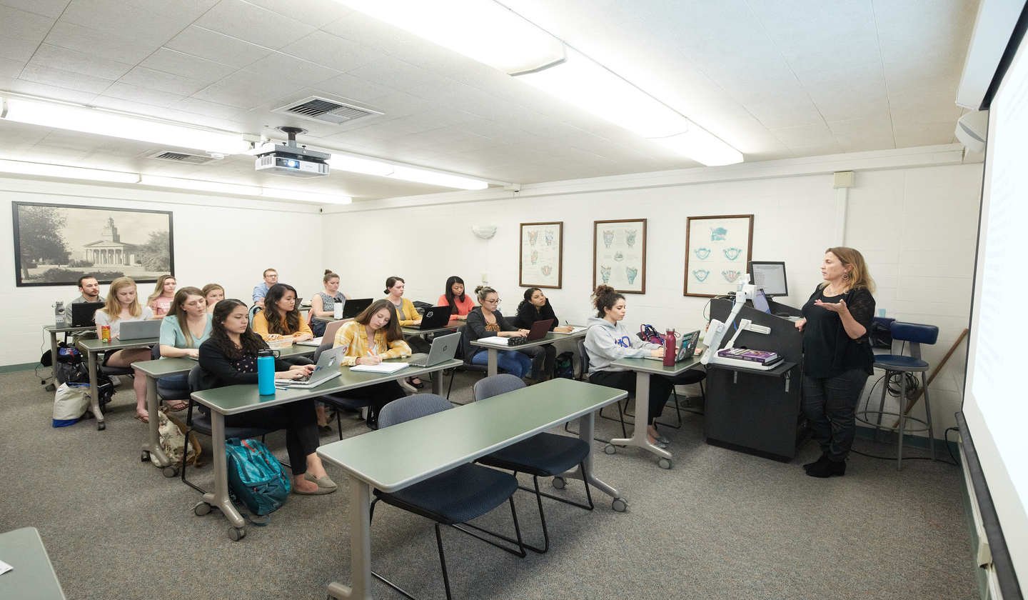 a person standing in front of a group of people in a classroom