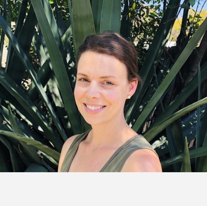 a woman smiling in front of a plant