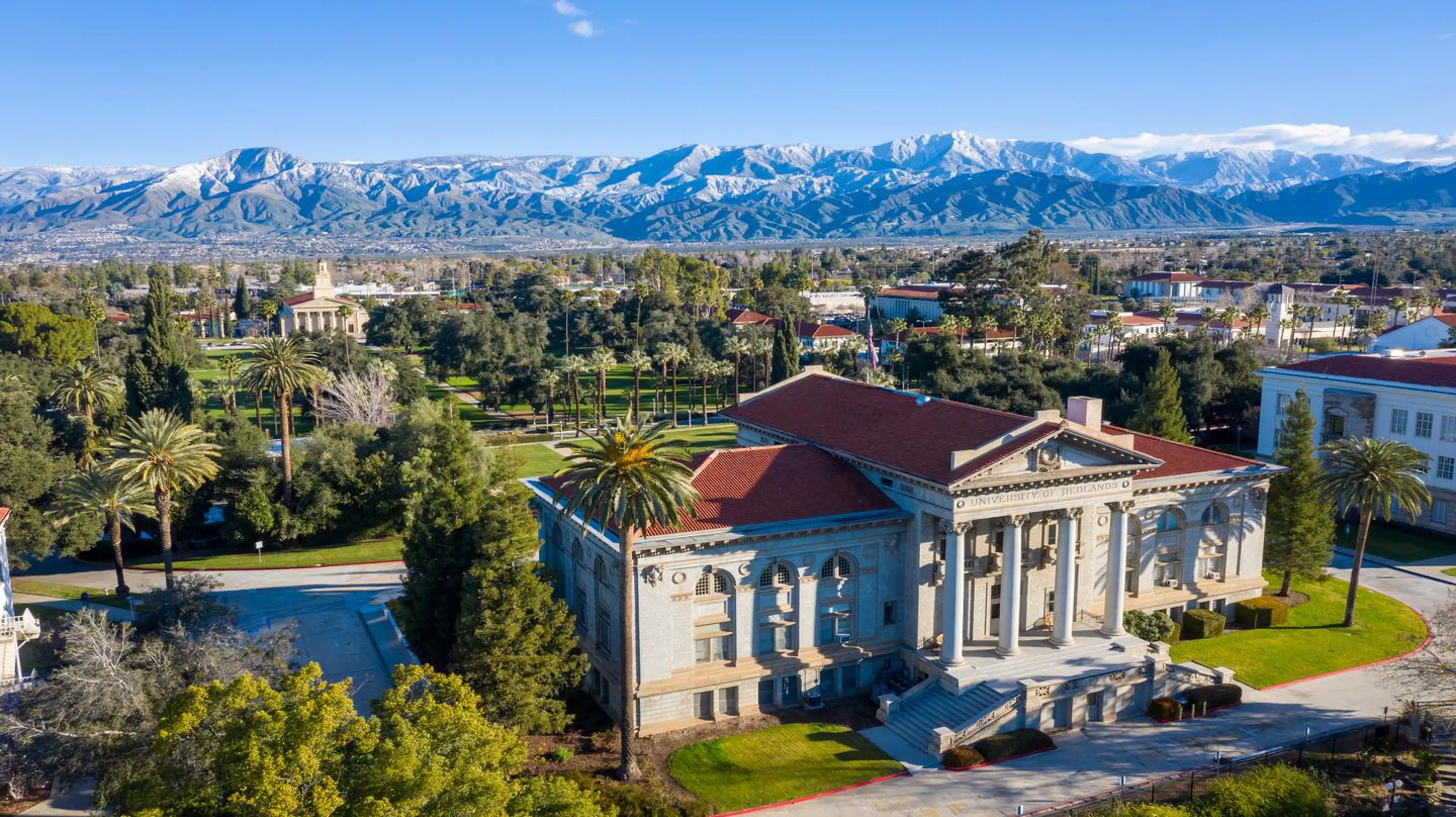 a large building with a large tree and mountains in the background