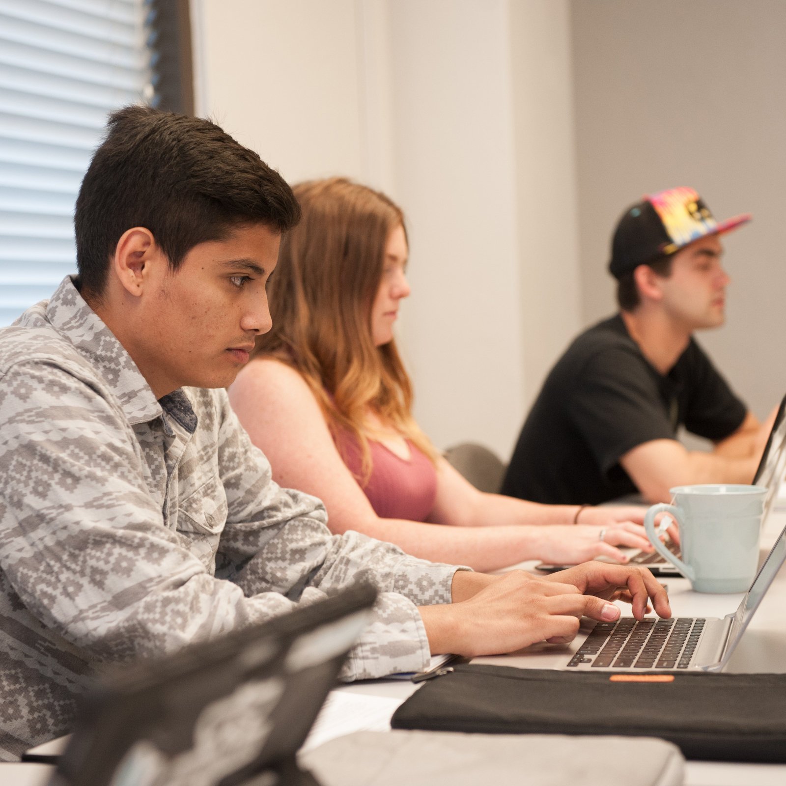 a group of people sitting at a table using laptops