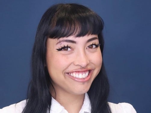 a person with piercings and nose ring smiling