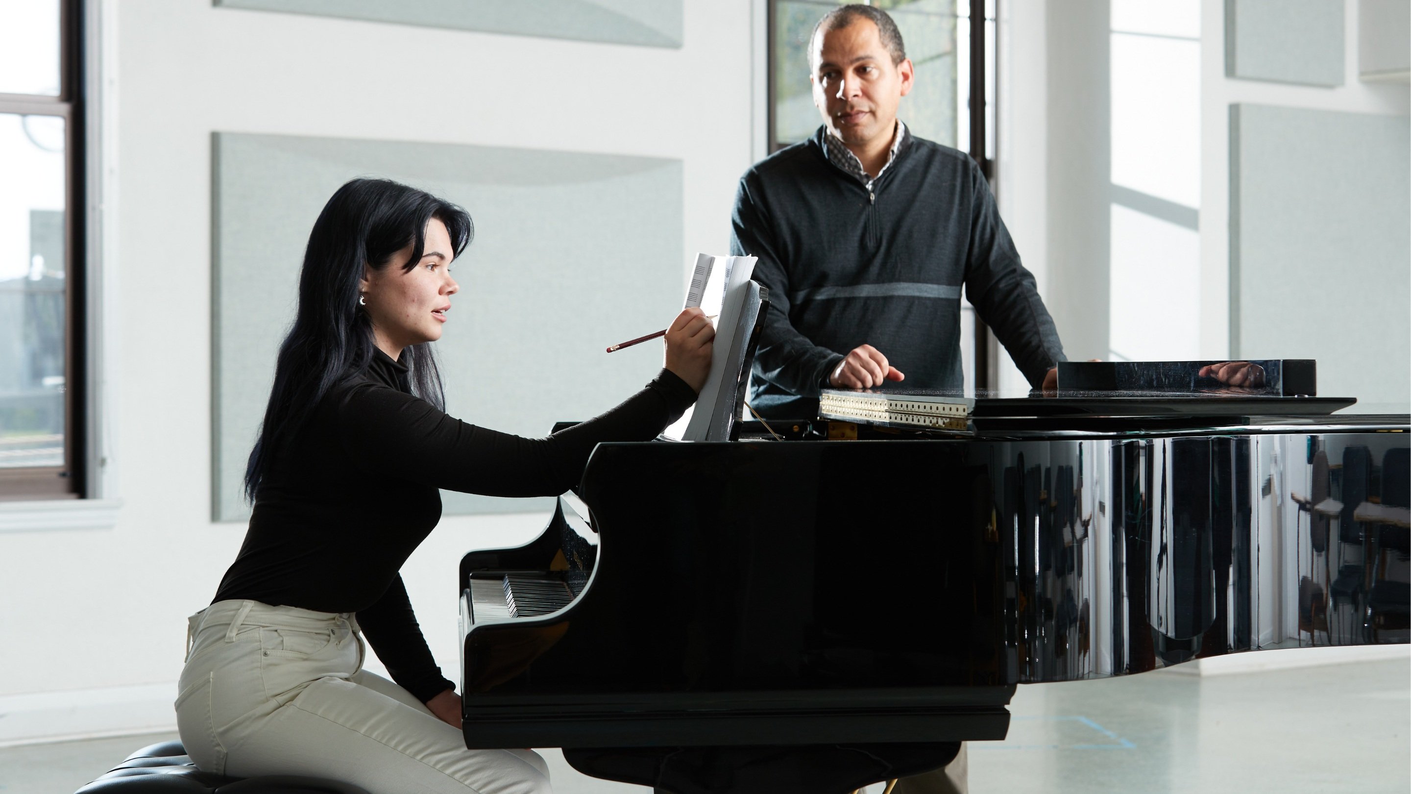 a person and person sitting at a piano