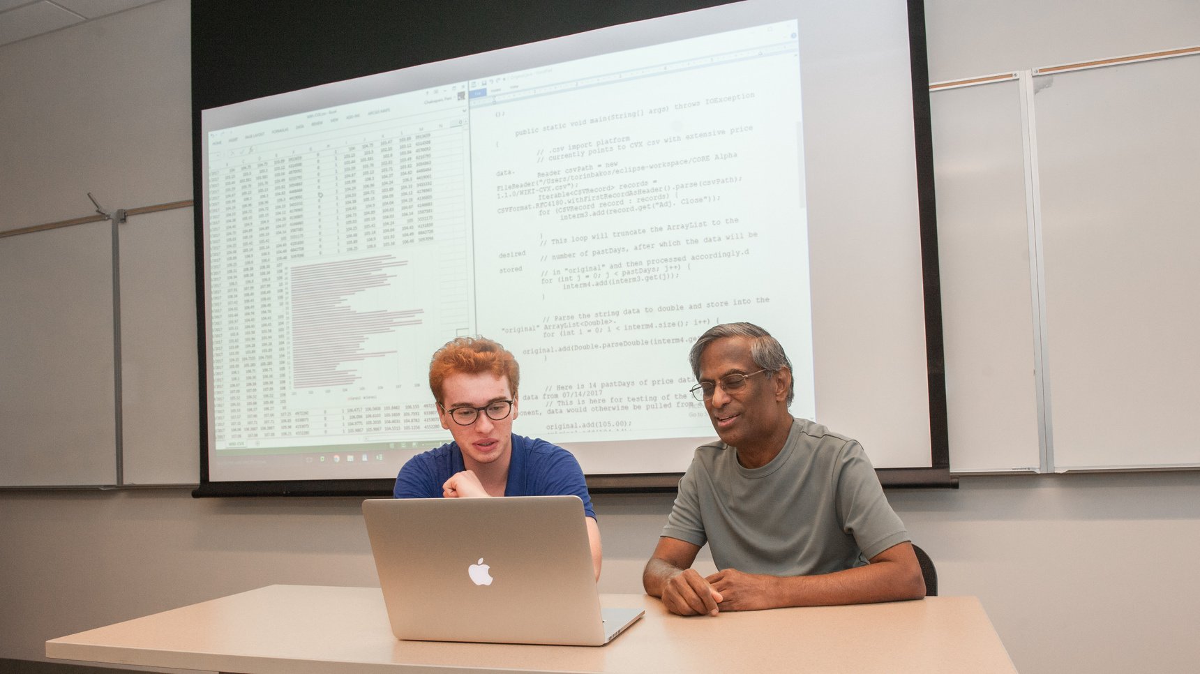 a person and person sitting at a table looking at a laptop