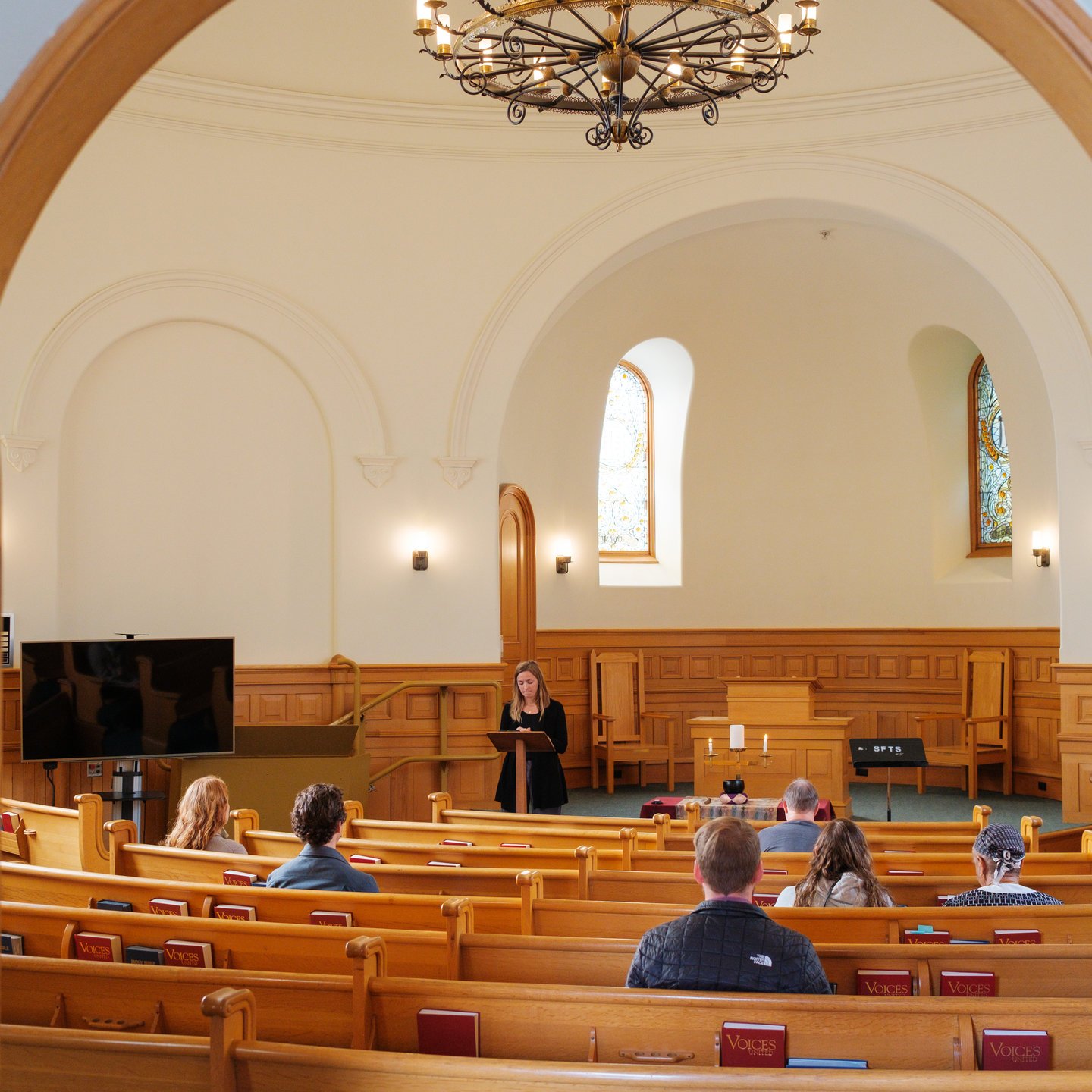 a woman standing in a room with a crowd of people