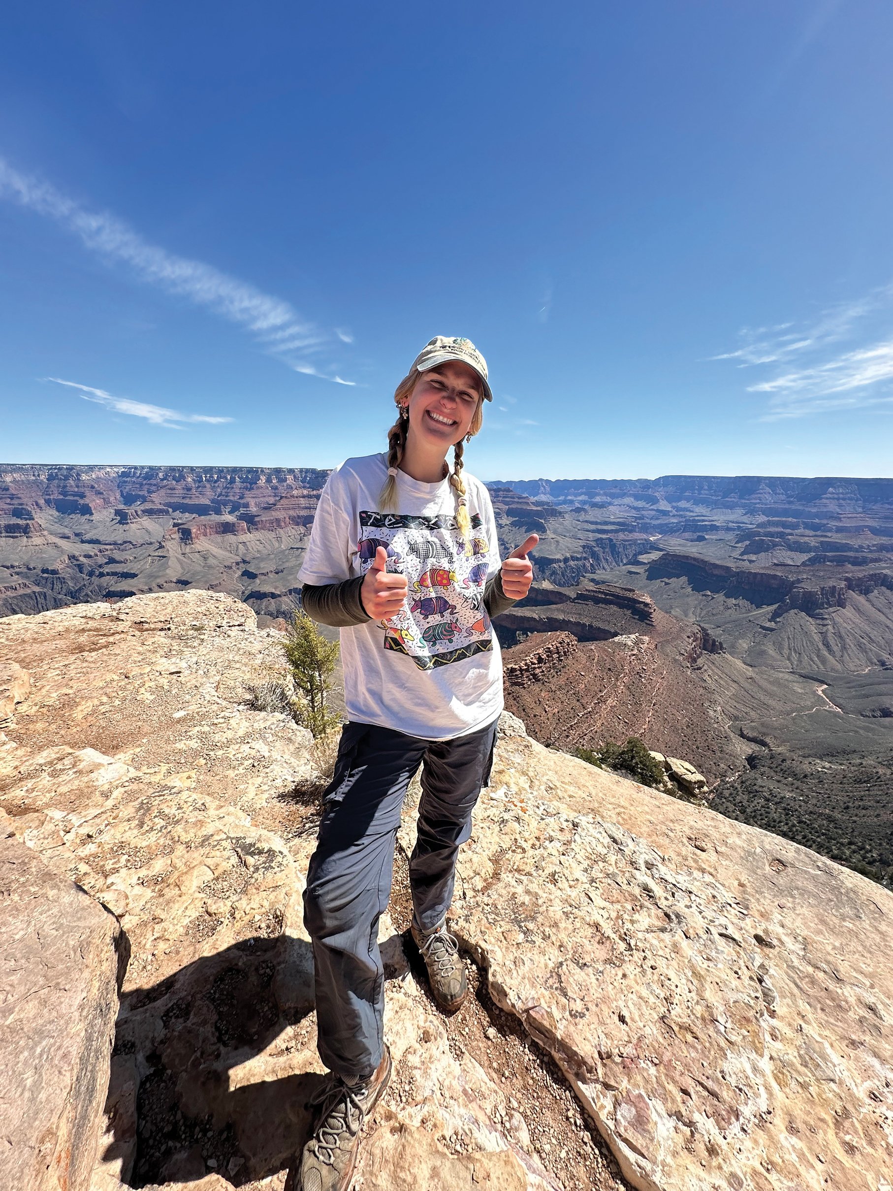 a woman standing on a rock with a view of the grand canyon