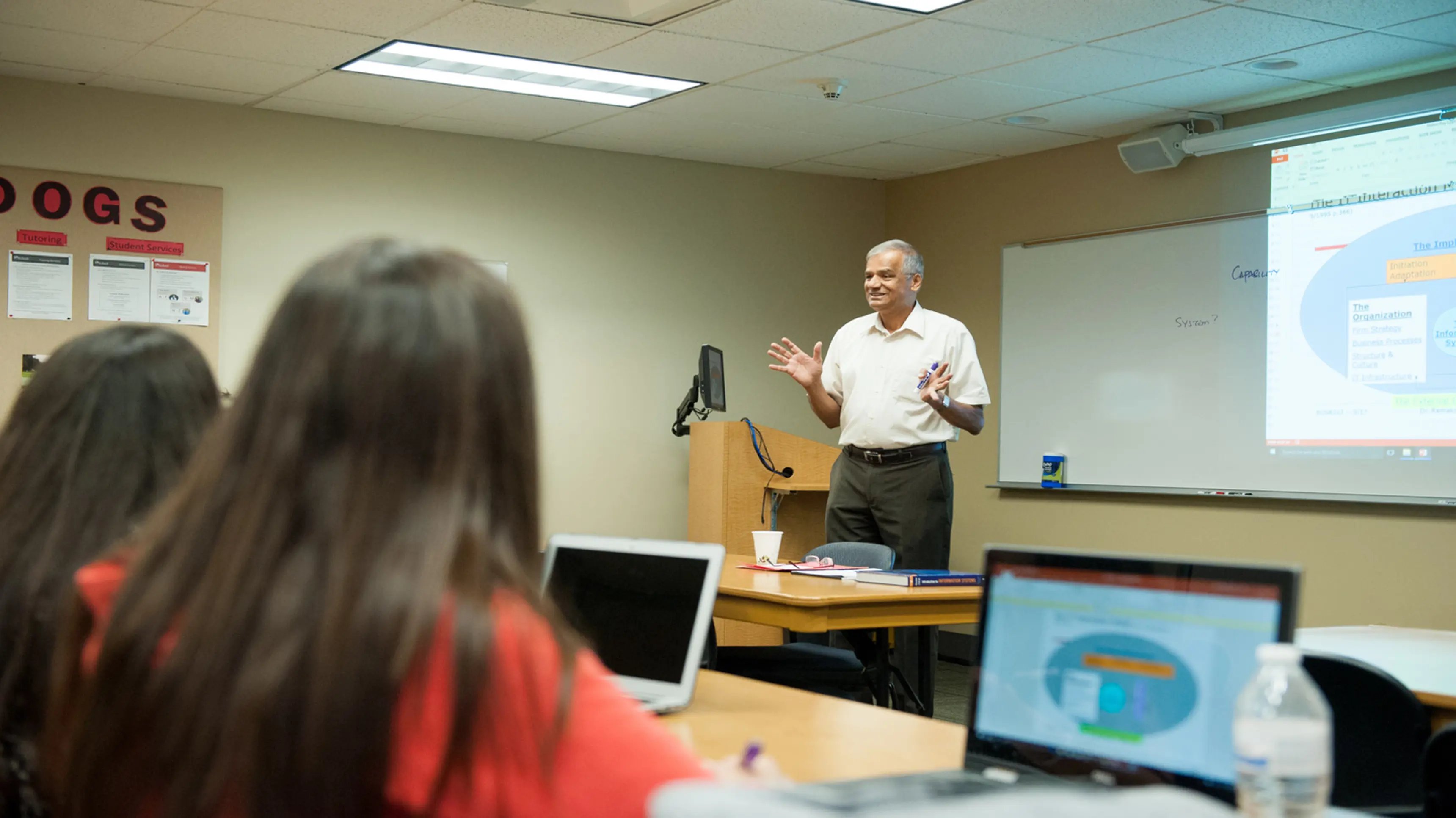 a person standing in front of a desk with a person in the background