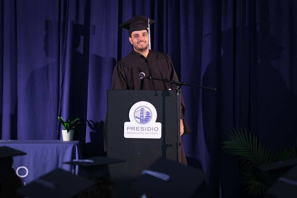 a man in a graduation gown standing at a podium