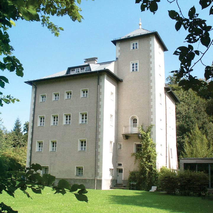 a large building with a lawn and trees in the background with Longthorpe Tower in the background