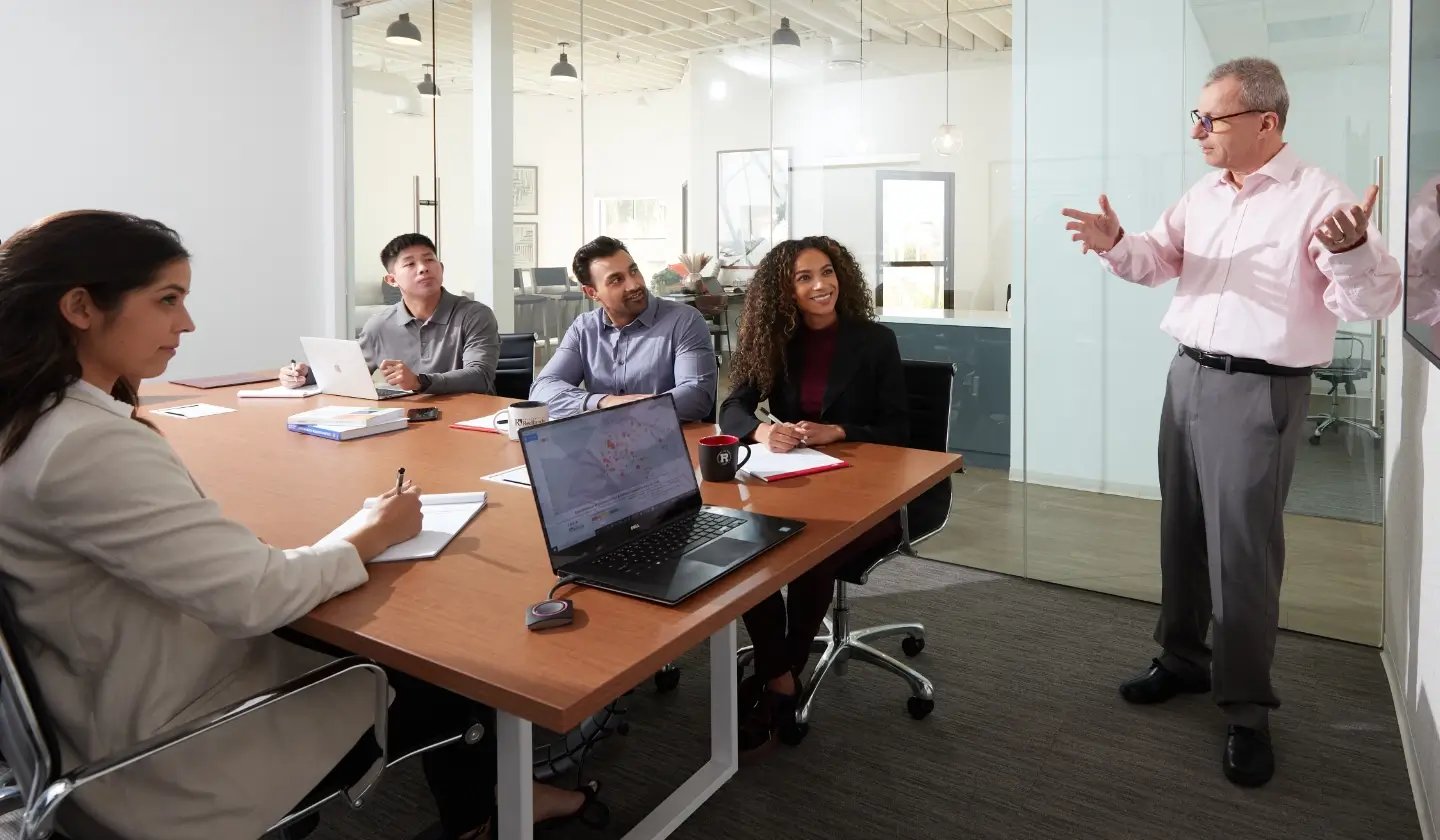 a person standing in front of a person pointing at a whiteboard