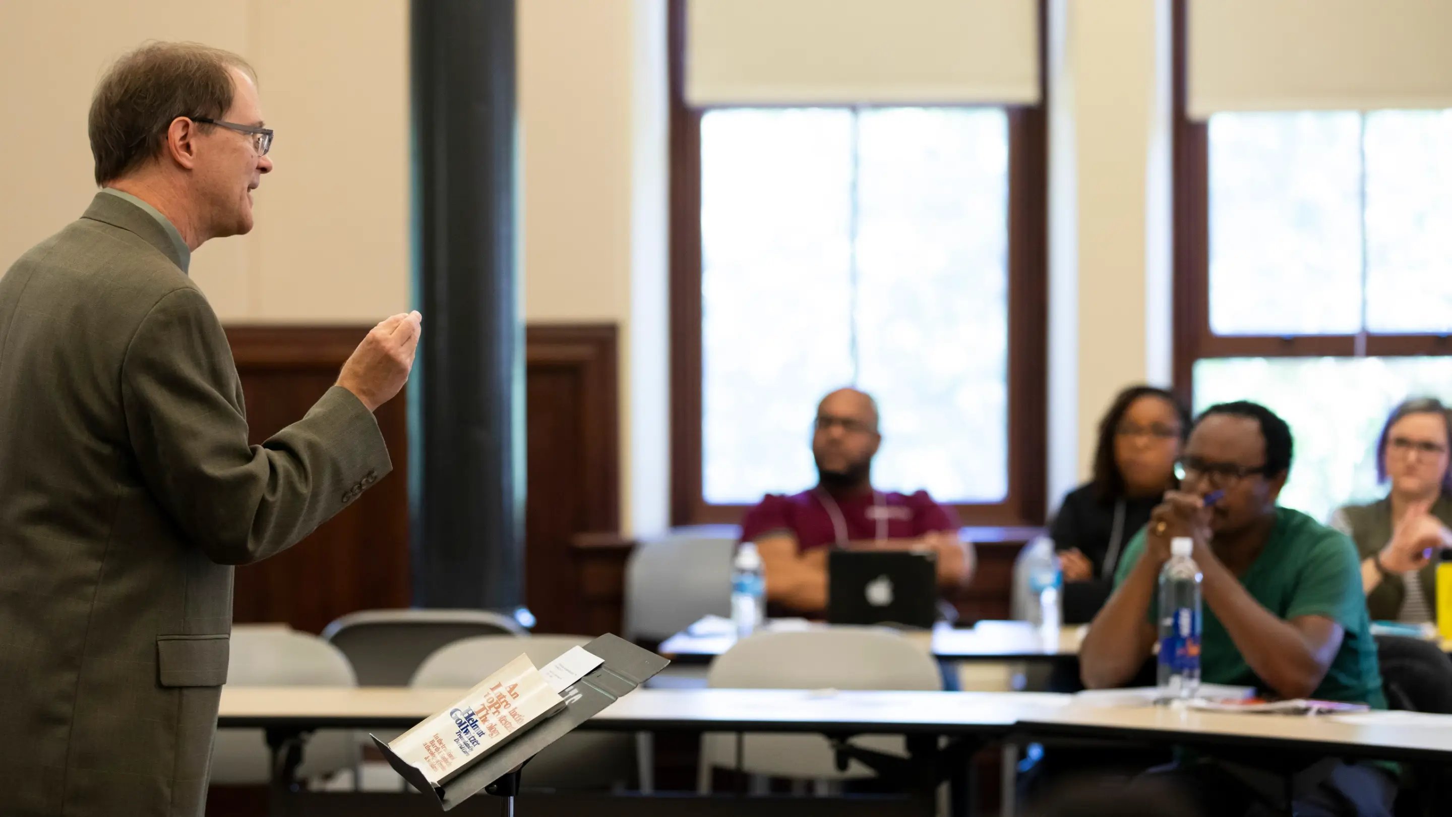 a man standing in front of a podium with a microphone and a man standing in front of a podium with a man standing in front...
