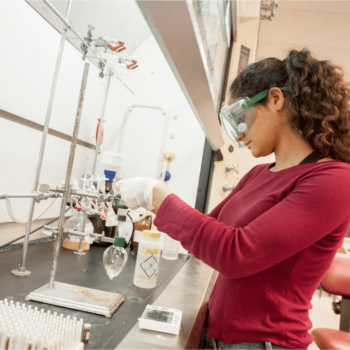 a person wearing safety goggles and gloves working in a lab