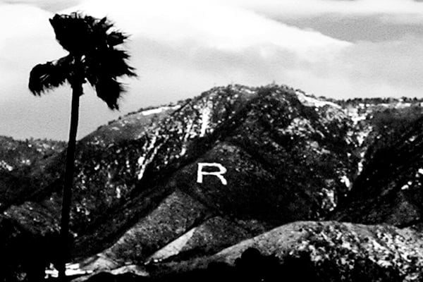 A black and white photograph of the mountains above Redlands with the letter R on the side of a mountain