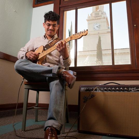 Guitar player practicing the strings in the School of Music. Guitar player practicing the strings in the School of Music.
